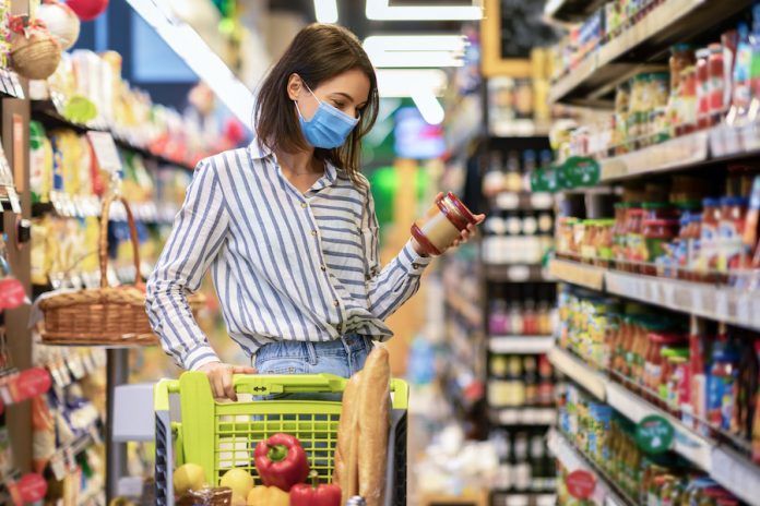 Young Woman In Mask With The Cart Shopping In Hypermarket