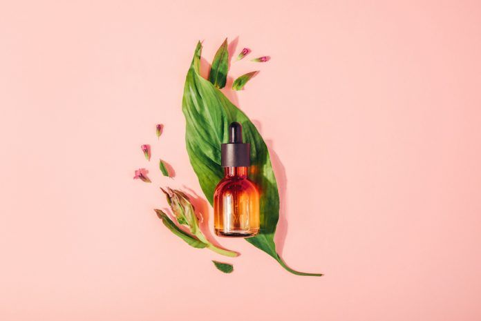 Bottle With Natural Serum With Vitamins On A Pink Background. Cosmetic Procedures For The Face