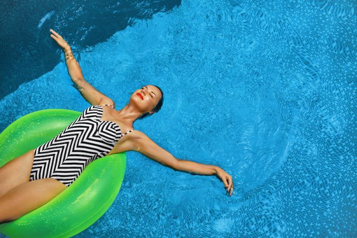 Summer Vacations. Woman Sunbathing, Floating In Swimming Pool Water. Wellness